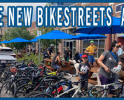 A large group of parked bicycles and outdoor cafe seating with several people
