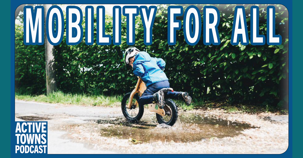 A child coasting on a balance bike through a mud puddle