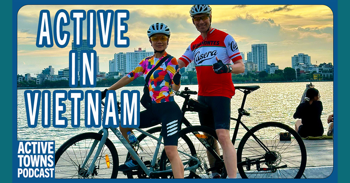 Dieter and Grace giving a thumbs up sign with their bicycles overlooking the water