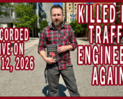 Wes holding a copy of his book in the middle of the street
