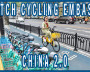A women riding in a protected bike lane in China past a line of colorful shared bikes